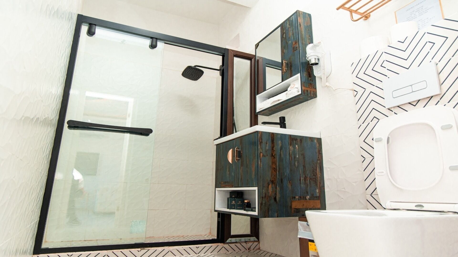 A bathroom with a glass shower enclosure, a white toilet, and a vanity with a rustic design.