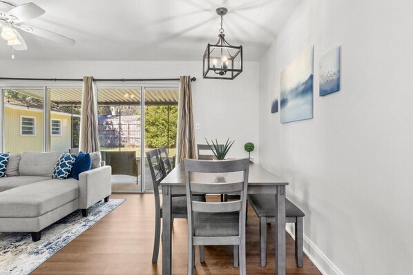 A modern living room with a grey sectional sofa, a dining table with chairs, a ceiling fan, and a chandelier. - Stylish and Comfortable Escape in Gainesville (Gainesville)
