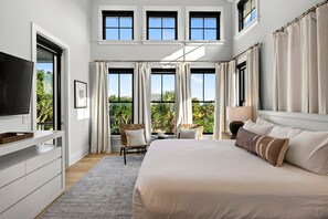 A modern hotel room with a large bed, a television, and a balcony with curtains.
