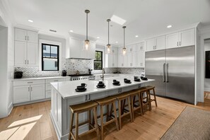 A modern kitchen with white cabinetry, a stainless steel refrigerator, and a central island with stools.