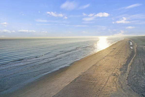 A beach with a wide sandy shore and gentle waves, under a clear sky.