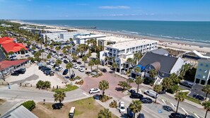 Vista aérea de un pueblo costero con playa, estacionamientos y edificios con comercios.