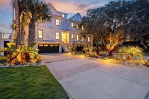 A two-story house with a driveway, palm trees, and a well-maintained lawn.