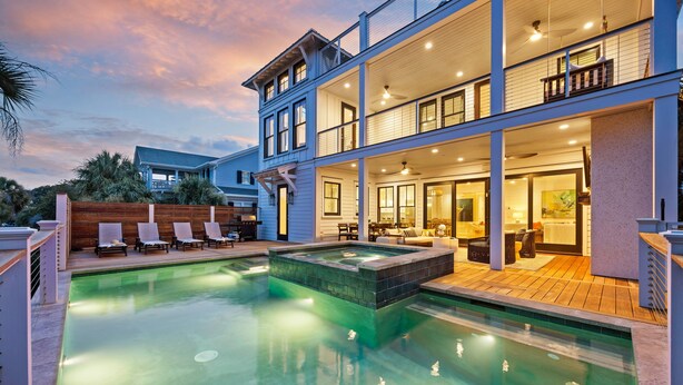 Une maison à deux étages avec une piscine, un espace salon extérieur et une terrasse couverte.