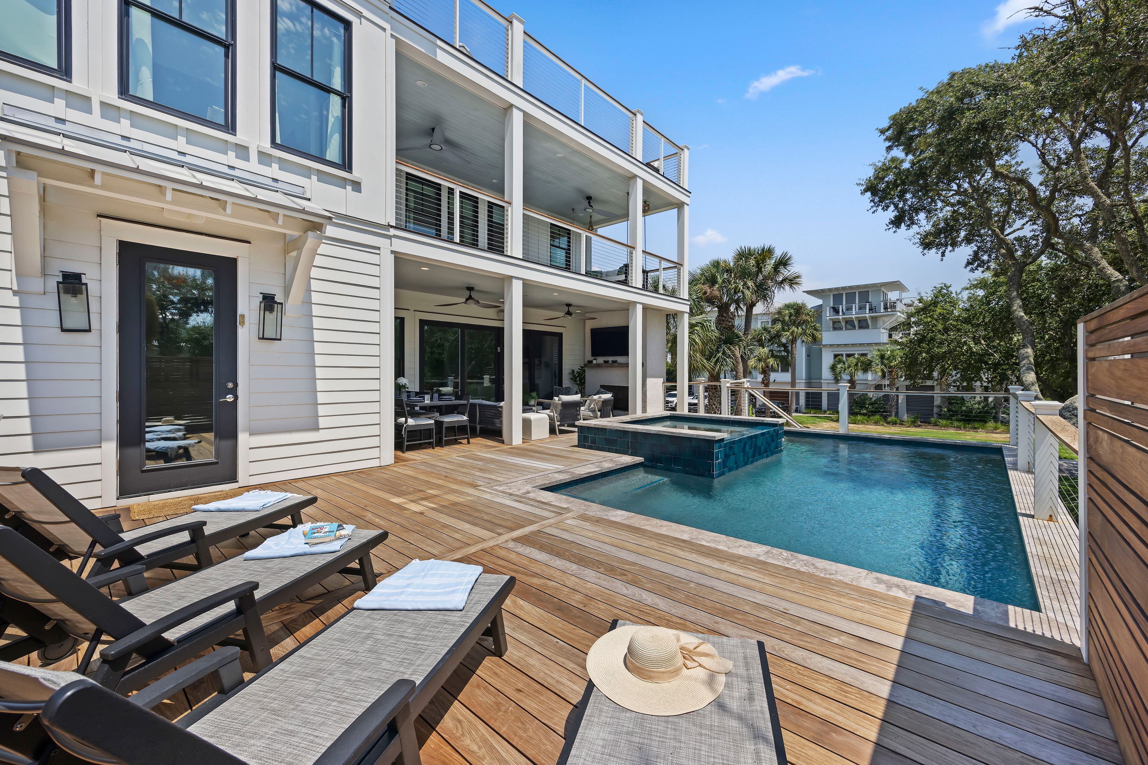 Ein zweistöckiges Haus mit Swimmingpool, Gartenmöbeln und einer überdachten Terrasse.