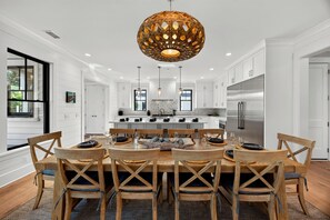 A modern kitchen with white cabinetry, a central island, and a large stainless steel refrigerator.