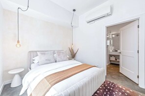 Ein Schlafzimmer mit Bett, Nachttisch und einer offenen Tür zu einem Badezimmer.