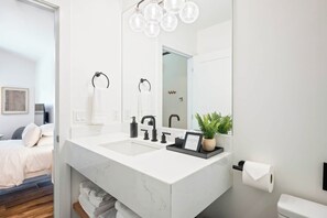 Ein modernes Badezimmer mit einem Doppelwaschbecken, einem großen Spiegel und einer Topfpflanze.
