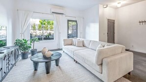 A modern living room with a sofa, a coffee table, and potted plants.