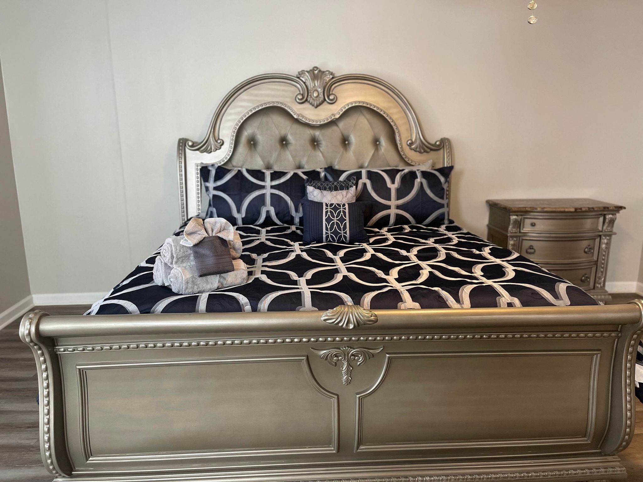 A bed with a tufted headboard, a patterned bedspread, and a decorative pillow.