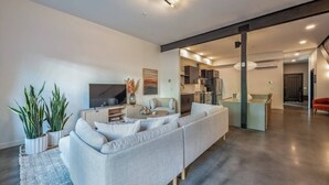 Un salon moderne avec un grand canapé, un téléviseur à écran plat et des plantes en pot.