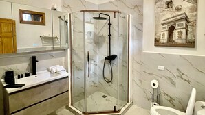 Et moderne badeværelse med bruseniche, vaskebord med spejl og toilet.