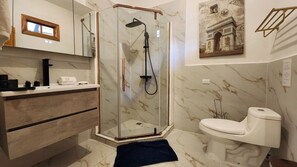 Een badkamer met een douchecabine van glas, een wit toilet en een marmeren vloer.