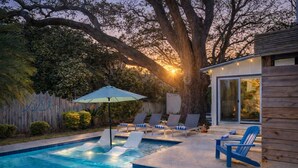A backyard with a swimming pool, lounge chairs, and a wooden deck. - Goin' Coastal: East Beach 5BR Retreat | Private Pool | Steps to Beach | Sleeps 12 (Saint Simons Island)