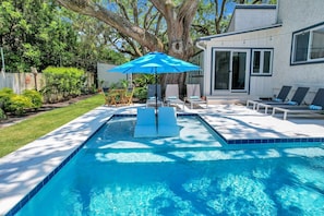 Relax by the pool surrounded by lush greenery and comfortable lounge chairs.