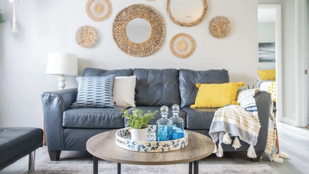 A living room with a grey sofa, a round coffee table with a tray, and decorative wall art.