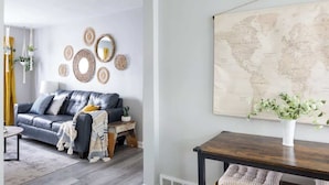 A living room with a grey sofa, decorative wall art, and a world map.