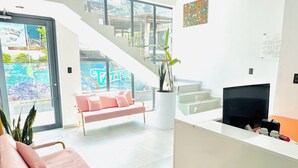 A modern reception area with a pink sofa, a reception desk, a staircase, and a large window with a view.