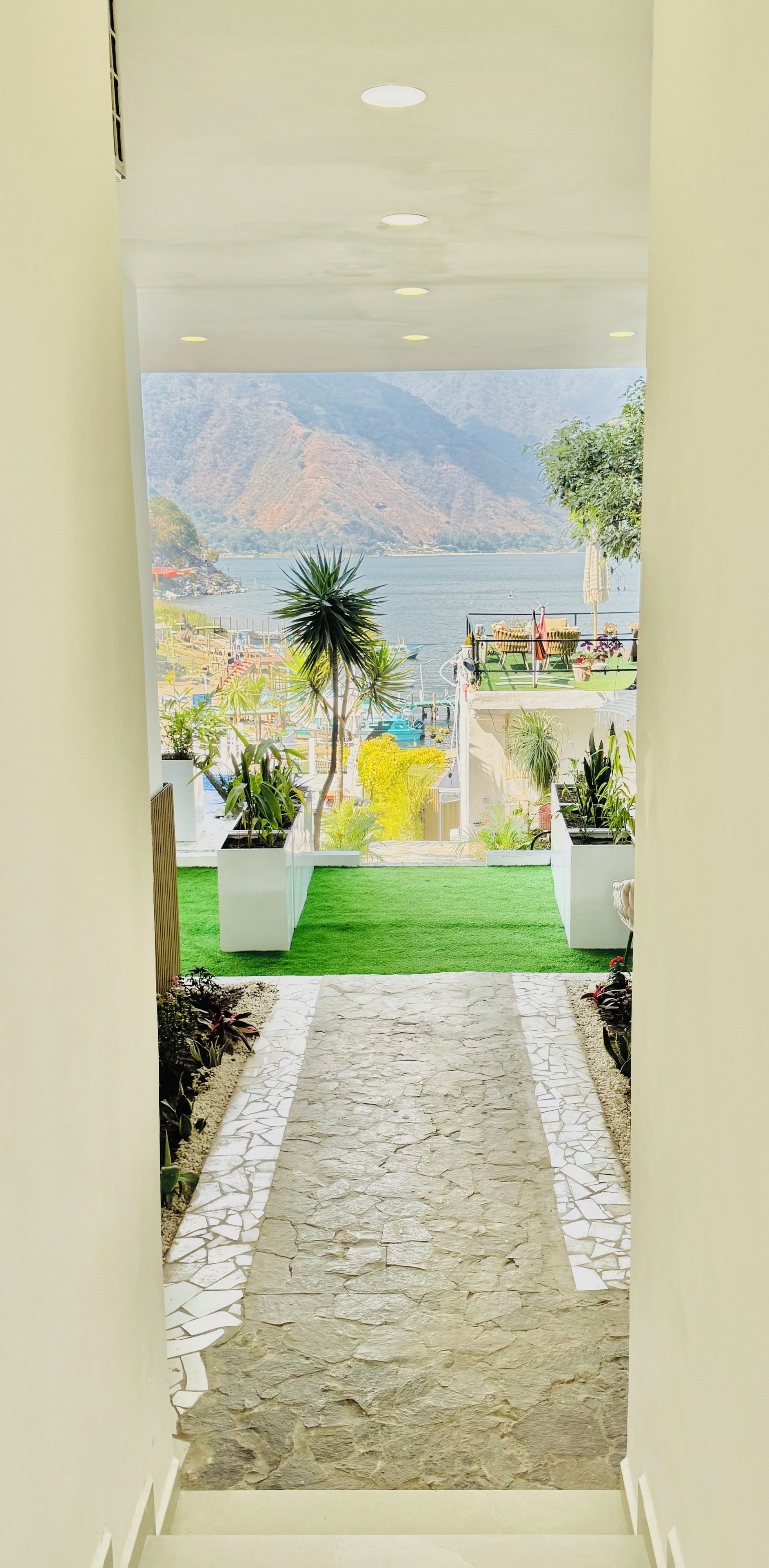 A pathway leading to a balcony with a view of a body of water and mountains.