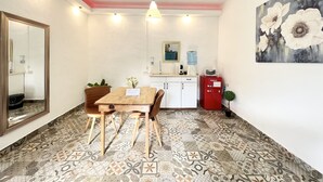 A small, well-lit room with a wooden table, chairs, a mirror, a water dispenser, a microwave, and a red cabinet.