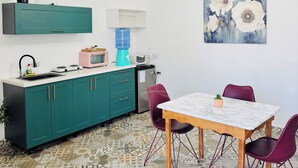 A modern kitchen with teal cabinets, a white countertop, and a patterned tile floor.