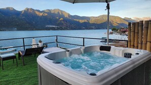 Ein Whirlpool mit Bergblick, eine Rasenfläche und ein Geländer.
