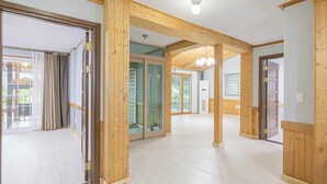 A spacious hallway with wooden beams, a glass door leading to an outdoor area, and a ceiling light fixture. - Gyeongju Cabinhouse (Gyeongju)