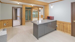 A modern kitchen with a central island, wooden paneling, and a view to a balcony. - Gyeongju Cabinhouse (Gyeongju)