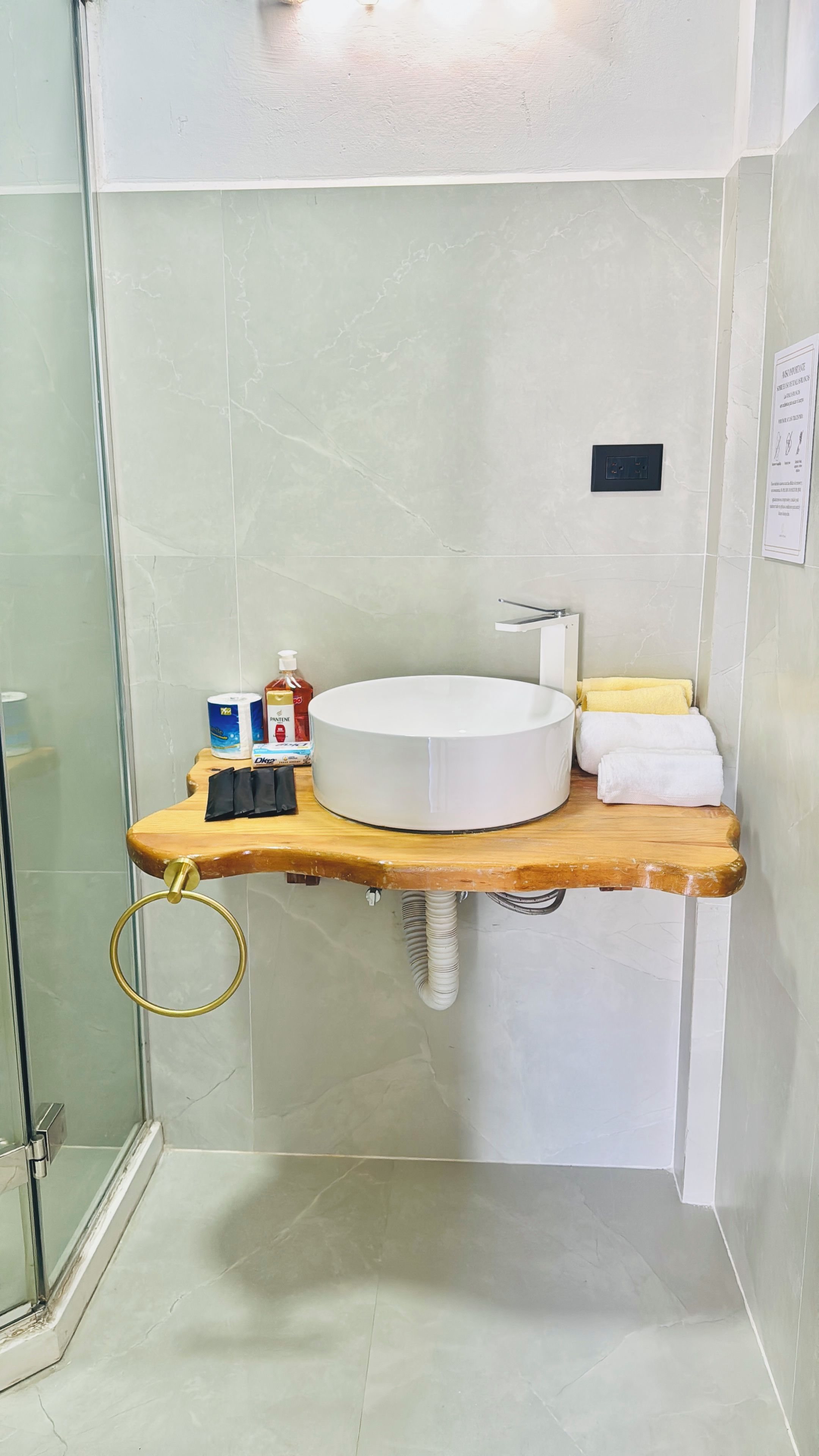 A bathroom with a round sink, a wooden countertop, and a glass shower enclosure.