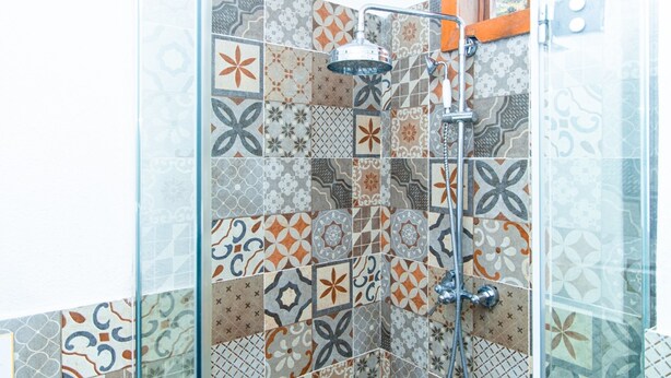 A shower with a glass door and a patterned tile wall. - VENICE by luxury atitlan (San pedro la Laguna solola)