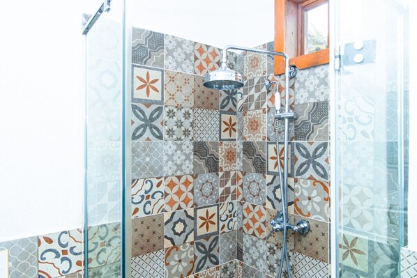 Une douche avec une porte en verre et un mur recouvert de carreaux décoratifs.