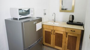 Une cuisine compacte équipée d’un réfrigérateur, d’un four à micro-ondes, d’un évier et d’une machine à café.