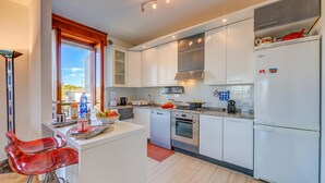 A modern kitchen with white cabinets, a built-in oven, and a refrigerator. - Casa di Paola: Lake-View Balcony Apartment in Peschiera, Peschiera del Garda, Italy (Peschiera del Garda)