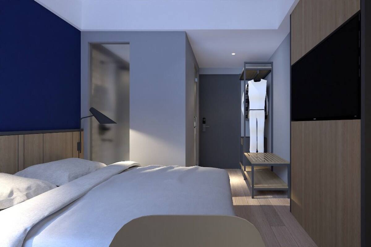 A modern hotel room with a bed, a desk, and a TV.