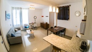 A modern living room with a sofa, a dining table, and a kitchen area with a toaster. - San Pedro Suite (San pedro la Laguna solola)
