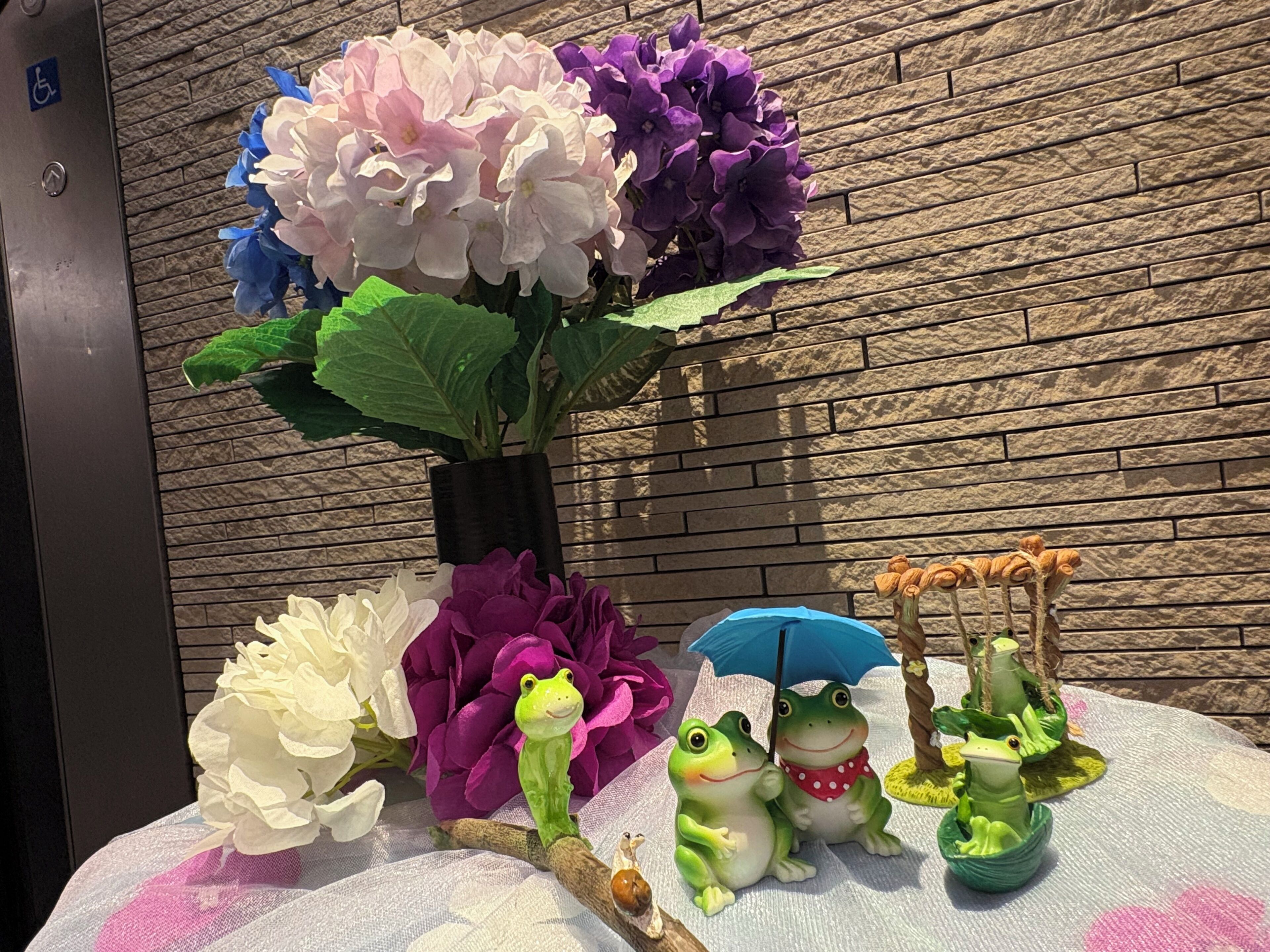 A table with a vase of flowers, a frog figurine, and a frog sculpture.