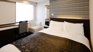Une chambre d’hôtel avec un grand lit, une chaise, un bureau et une fenêtre.