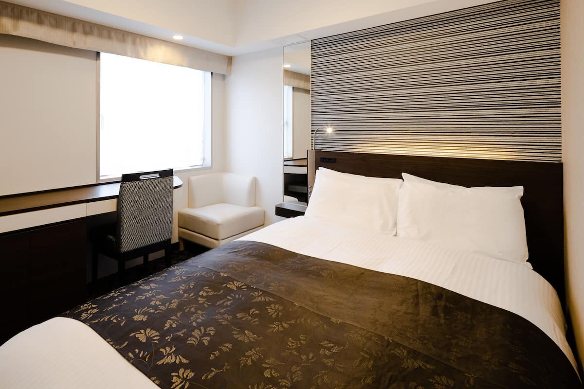 Een hotelkamer met een groot bed, een stoel, een bureau en een raam.