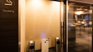 Un espace réservé aux fumeurs, équipé d’une poubelle et d’un conteneur de recyclage.