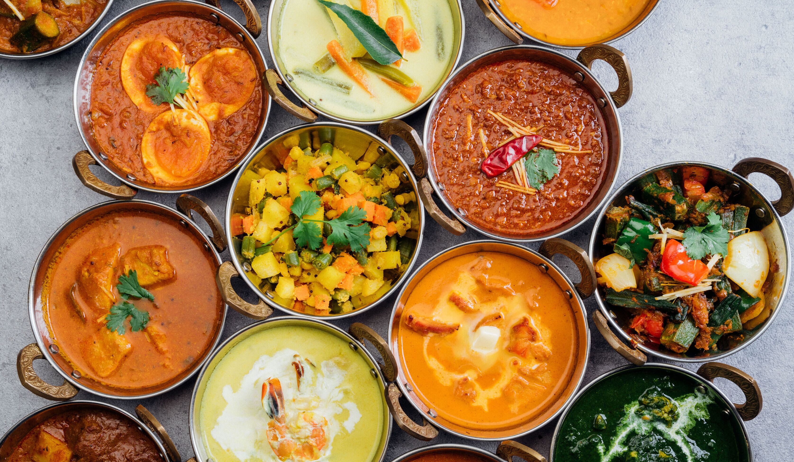 A variety of Indian dishes in metal bowls.