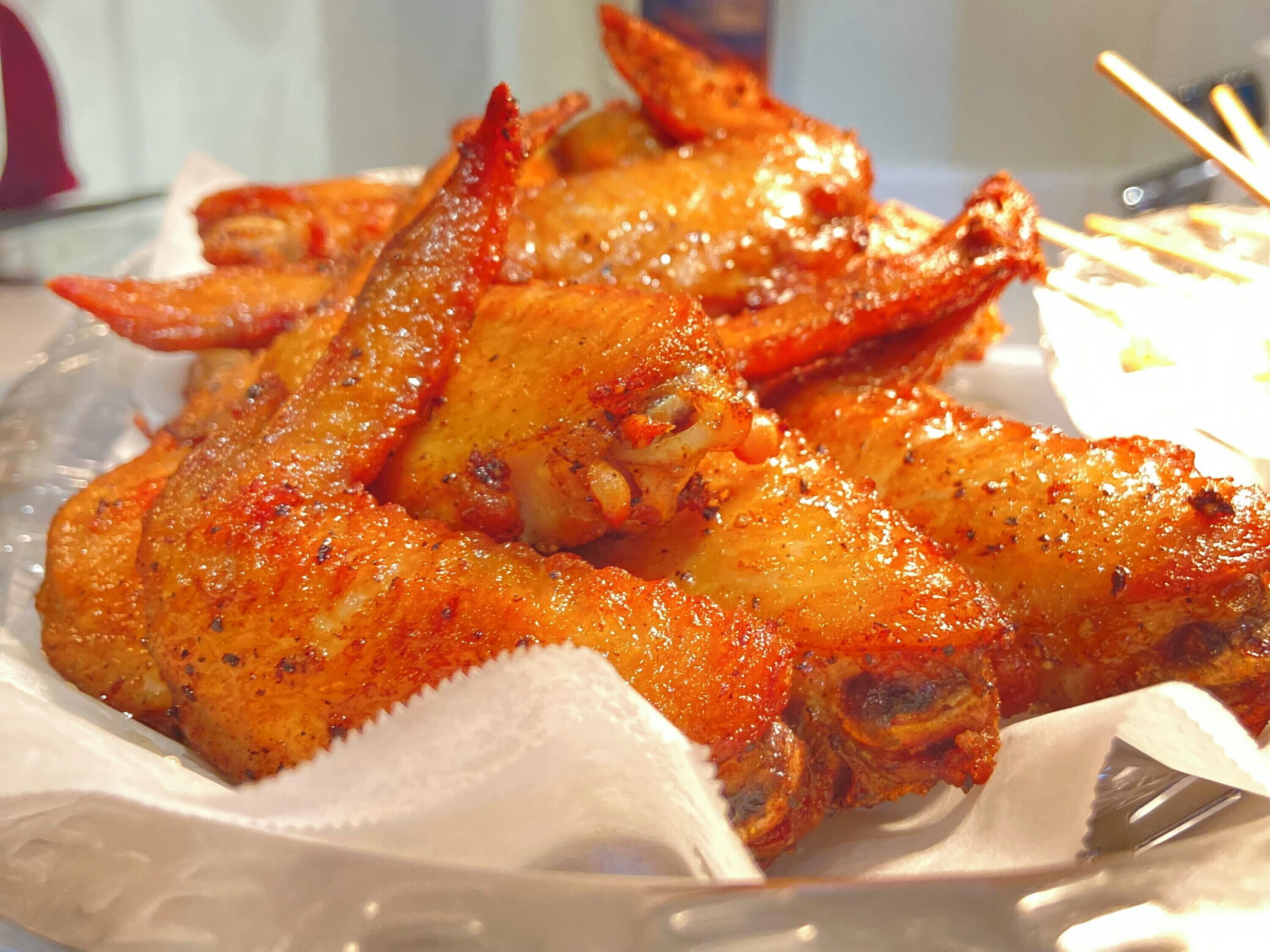 A plate of cooked chicken wings with a reddish seasoning.
