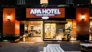 L’extérieur de l’hôtel APA présente un design moderne, avec une enseigne bien visible et des fenêtres illuminées.