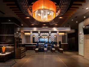 Un hall d’entrée moderne avec un grand lustre, un comptoir d’accueil et un espace salon.