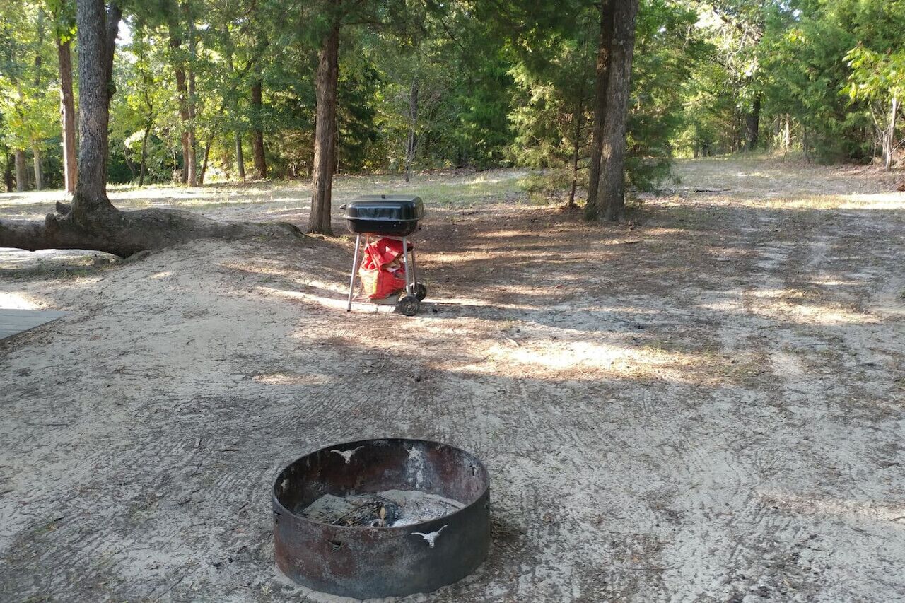 A campsite with a portable grill and a fire pit.