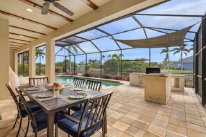 Um pátio externo com piscina, mesa de jantar e cadeiras.