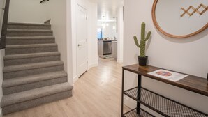 Eine Treppe führt zu einer Küchenzeile mit Holzboden, einem Kaktus auf einem Tisch und gerahmten Kunstwerken an der Wand.