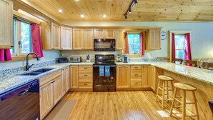 A kitchen with wooden cabinets, a microwave, a stove, and a sink.