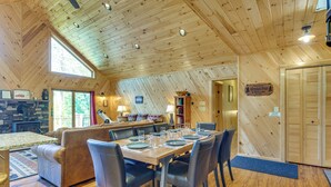 A cozy lodge interior with a dining area, a fireplace, and a view of the outdoors.