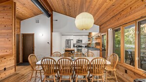 Une cuisine moderne avec des meubles blancs, des appareils en acier inoxydable et une table à manger en bois, accompagnée de six chaises.