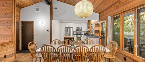 A modern kitchen with white cabinets, stainless steel appliances, and a wooden dining table with six chairs.
